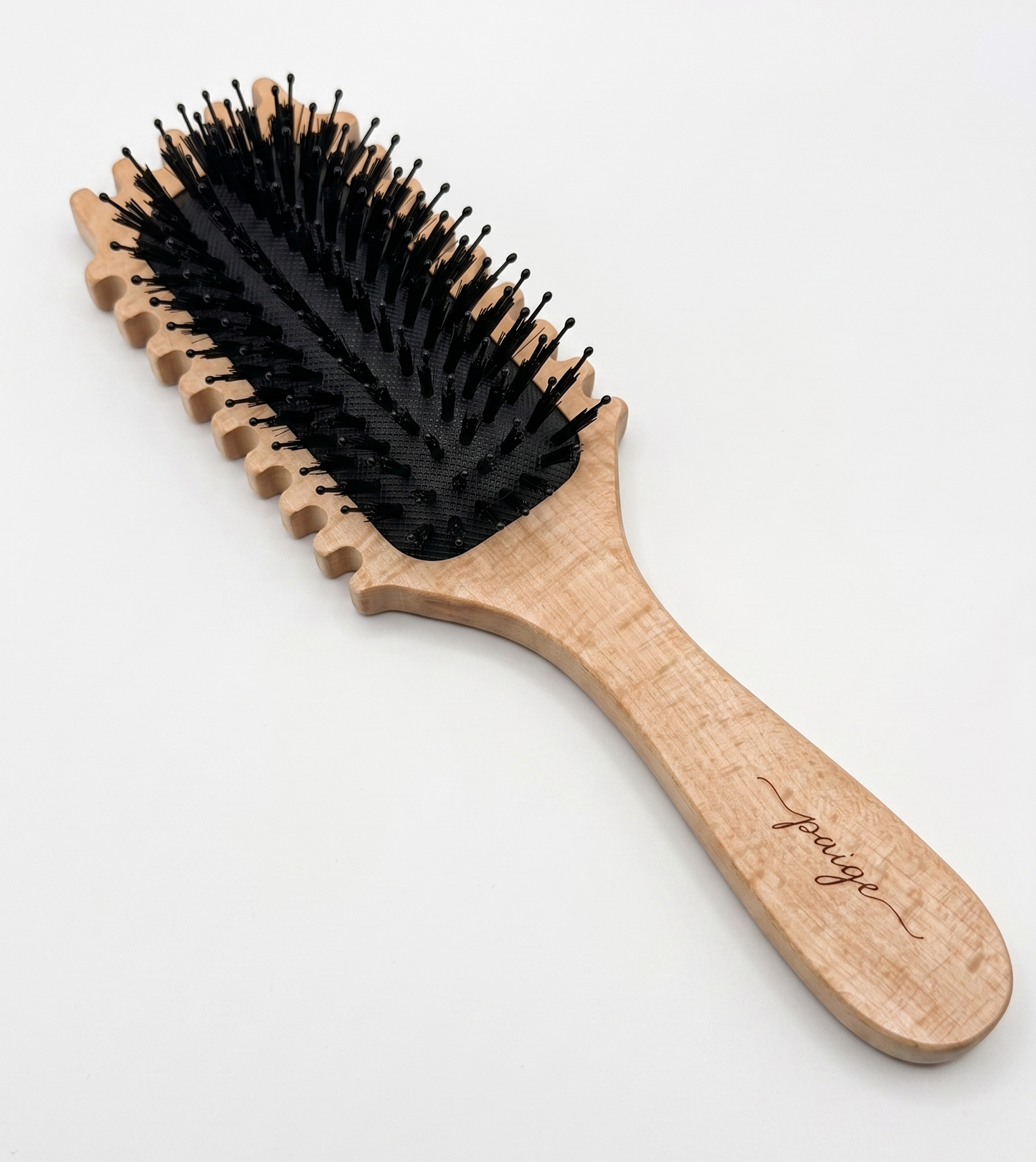 Luxury detangling brush for curly hair styled on a vanity with natural hair products.