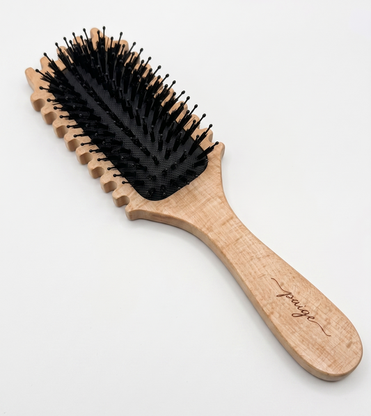 Luxury detangling brush for curly hair styled on a vanity with natural hair products.